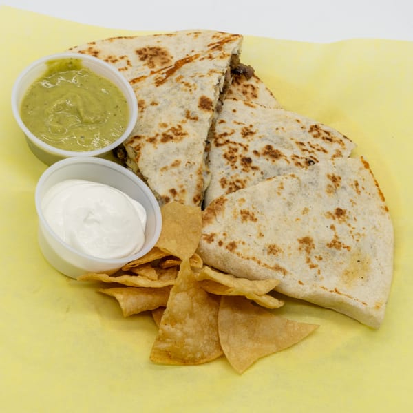 Quesadillas with guacamole, sour cream, and tortilla chips on yellow paper.